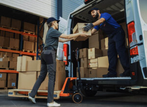 Außerhalb des Logistik-Vertriebslagers: Ein buntes Team von Mitarbeitern belädt den Lieferwagen mit Kartons, Online-Bestellungen und E-Commerce-Einkäufen.